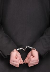 A picture of a businessman in handcuffs standing over white background